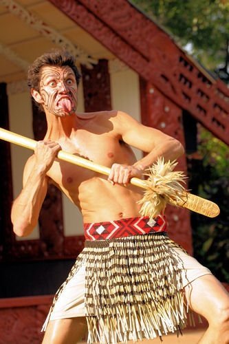 This image shows the ta moko on his face, the taiaha in his hands, the marae behind him, and a fine Maori warrior. This image was taken at the Maori village in the Polynesian Cultural Center.