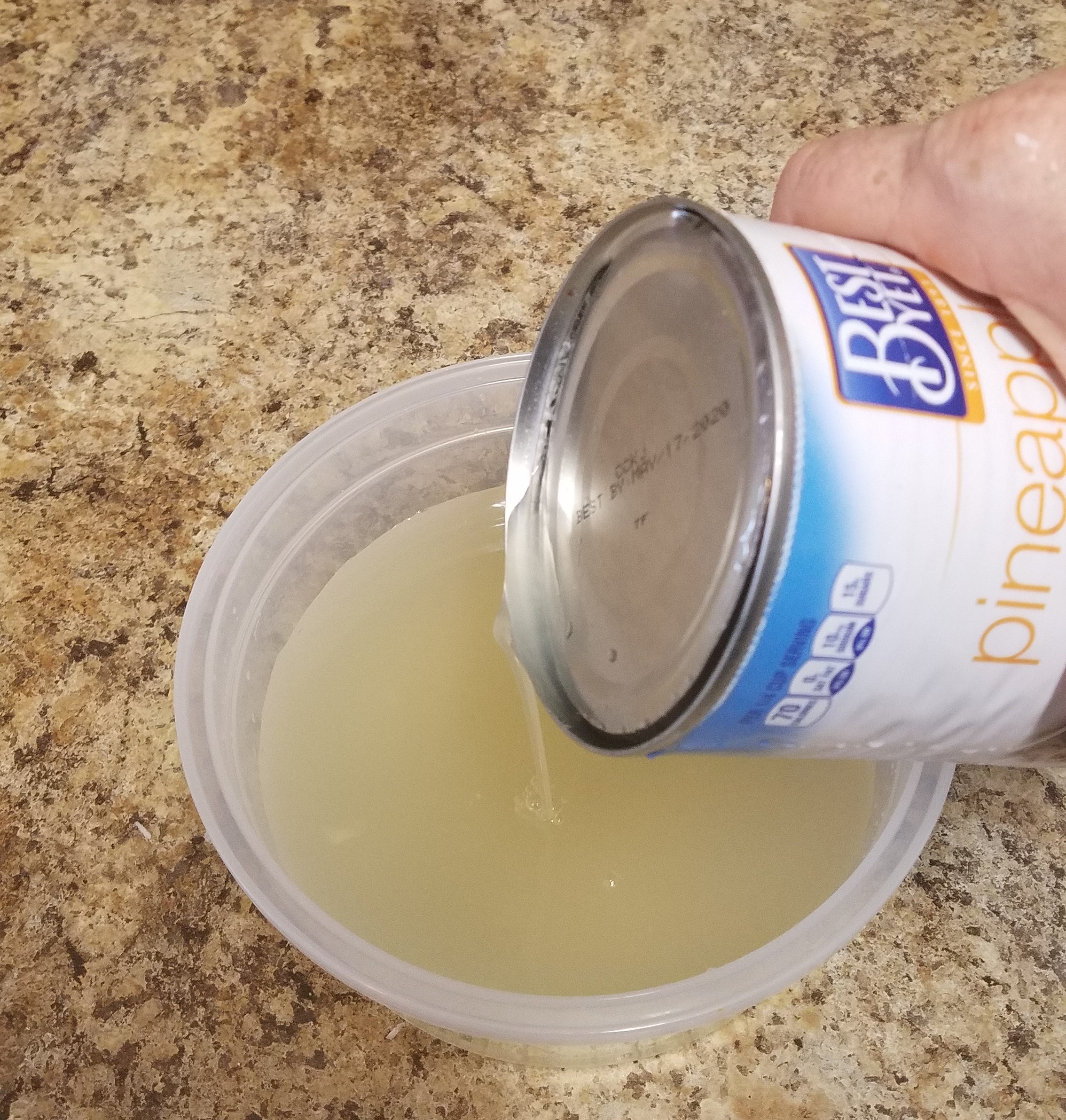 photo of pineapple juice being drained from a can of pineapple