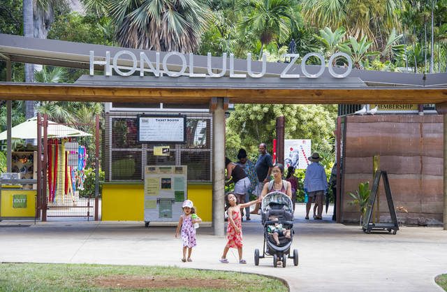 photo of Honolulu Zoo front entrance with a mom and 2 kids walking out the Zoo. One of the 5 things to do with your children. 