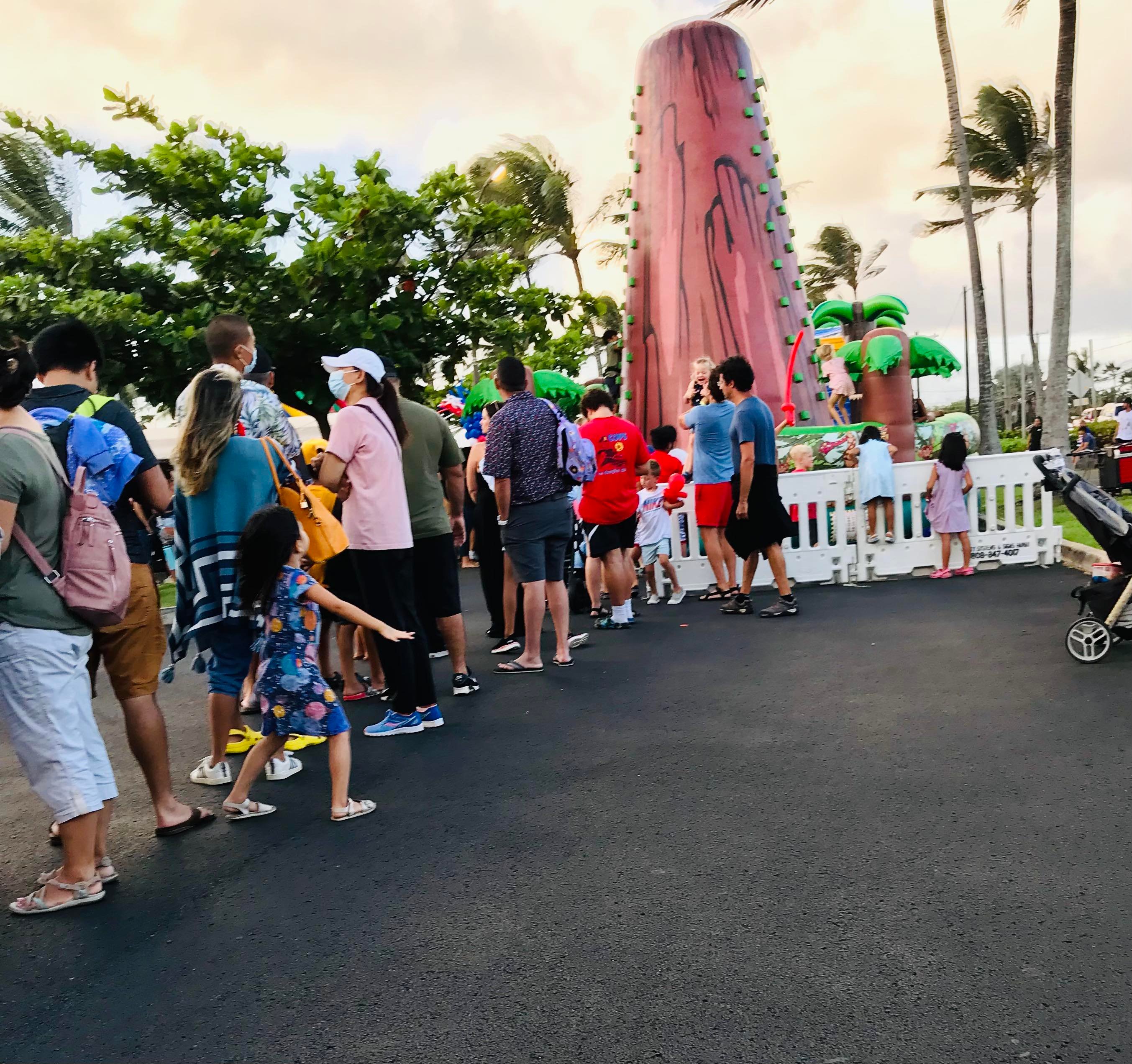 Kids enjoy rock climbing at the 4th of July event. A long queue of parents with their kids waiting for their turn to rock climbing.